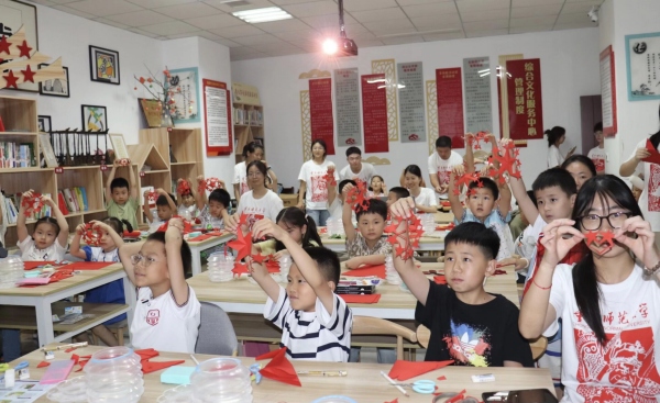 实践团成员与孩子们共同创作剪纸作品。bw必威西汉姆联官方网站美术学院供图